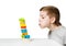 Portrait of a boy blowing on falling house made of wooden blocks