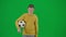 Portrait of boy on chroma key green screen. Schoolboy in casual walking holding football ball and looking around. Front