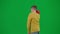 Portrait of boy on chroma key green screen. Schoolboy in casual walking holding red music speaker and listening to music