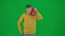 Portrait of boy on chroma key green screen. Schoolboy in casual walking holding red music speaker and listening to music