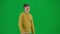 Portrait of boy on chroma key green screen. Schoolboy in casual walking and looking around, pointing finger holding hand