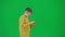Portrait of boy on chroma key green screen. Schoolboy in casual walking and playing video game on smartphone online