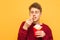 Portrait of a boy eating French fries with eyes closed on a yellow background. Young man and fast food. Copyspace