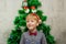 Portrait of a boy with funny glasses and christmas toys decorating cristmas tree and have fun
