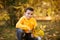 Portrait of a boy in hoodie posing with bunch of autumn leaves. Copy space