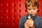 Portrait of boy with microphone against red wall