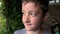 A portrait of a boy with a raindrops on a face and wet hair after downpour, bad weather and storm in summer