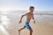 Portrait Of Boy Running Through Waves On Summer Vacation