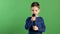 Portrait of boy singing to microphone on green light background, stylish cool guy, entertainment for kids, starting