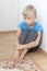 Portrait of boy sitting on floor looking away calm upset deep in thought