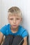 Portrait of  boy sitting on floor looking into camera calm upset deep in thought. Photo with selective focus