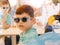 Portrait of a boy with sunglasses sitting in a wheelchair because of a motor disability of his body with his brother in the