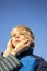 Portrait of a boy from Ukraine with a painted yellow-blue heart on his cheek and female hands gently hug his face