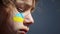 Portrait of a boy with the Ukrainian flag on the face of body painting.