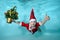 Portrait of a boy under water in a Santa Claus costume at the bottom of the pool. He is holding a Christmas tree