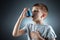 Portrait of a boy using an asthma inhaler to treat inflammatory diseases, shortness of breath. The concept of treatment for cough