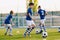 Portrait of boys in junior youth football team leading ball between cones during practice training in grass field