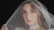 Portrait of bride face close-up under veil. Girl touching her veil. Wedding morning preparations before ceremony