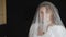 Portrait of bride face close-up under veil. Girl touching her veil. Wedding morning preparations before ceremony