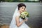 Portrait of the bride in a white dress in nature. Elegant bride holding her wedding bouquet