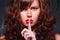 Portrait of brown-haired gorgeous young lady showing shhh taboo sign with finger to lips