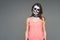 Portrait of brown-haired woman with terrifying halloween skeleton makeup in pink football and a tattoo on his arm over gray backgr