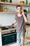 Portrait of brunet man with frying pan in his hands talking on phone in kitchen