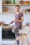 Portrait of brunet man with frying pan and phone in his hands in kitchen