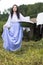 Portrait of Brunette Caucasian Girl With Basin of Laundry Against Hanged Linen on Rope Behind In Countryside Environment