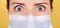 Portrait of a brunette girl with scary eyes in a medical mask, wide open eyes with horror