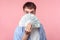 Portrait of brunette man with big amazed eyes peeking out of dollar bills. indoor studio shot isolated on pink