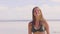 Portrait brunette woman shaking wet hair on sea beach. Cheerful woman with wet long hair shaking head on sea beach