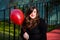 Portrait of brunette woman sitting outside holding a red balloon