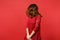 Portrait of brunette young woman in lace dress standing, jumping with fluttering hair isolated on bright red wall