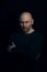 Portrait of a brutal bald man in a dark style on a black background. a guy in a black turtleneck boldly looks at the