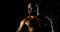 Portrait of a brutal muscular bald bearded male bodybuilder close-up on a black background, he poses, shows biceps, he