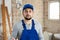 Portrait of builder man in blue overalls in room being renovated