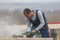 Portrait of builder working with circular saw outdoors, sawdust flying around