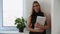 Portrait of business girl with documents near window in office. happy office worker woman.