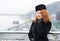 Portrait of business lady has rest on balcony. Aged women model in black coat and gloves. Woman on bridge waiting for meeting.
