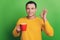 Portrait of business man guy drink coffee show okey gesture on green background