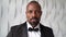 Portrait of a business man in a suit with a bow tie an African stands and looks at the camera on a white background.