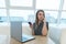 Portrait of a business woman with a phone in her hands sitting on a white laptop in a restaurant with a stylish design.