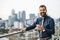 A portrait of businessman with smartphone standing against London view panorama.