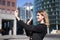 Portrait of businesswoman wave her hand at mobile phone camera, waves hand during video chat, stands in suit in city