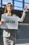 Portrait of businesswoman waving for her boss while holding blank white board in arrival area at airport