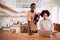 Portrait Of Busy Family In Kitchen At Breakfast With Father Caring For Baby Son