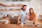 Portrait Of Busy Family In Kitchen At Breakfast With Father Caring For Baby Son