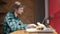 Portrait of busy young business man sitting with glass of drink and hamburger in fast food restaurant interior