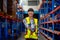 Portrait of Cacuasian warehouse worker hold barcode scaner and point at camera stay on way between shelves in workplace. Concept
